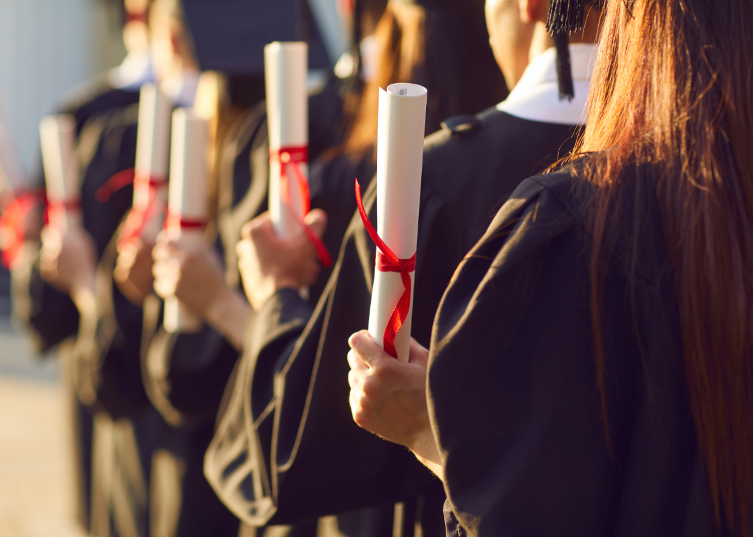 Students hold their diplomas at a college graduation